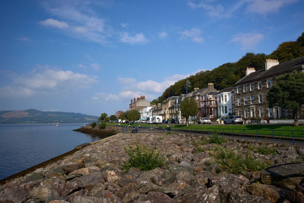 Picturesque view of Rothesay's coastal townhouses with lush greenery and a serene waterfront.