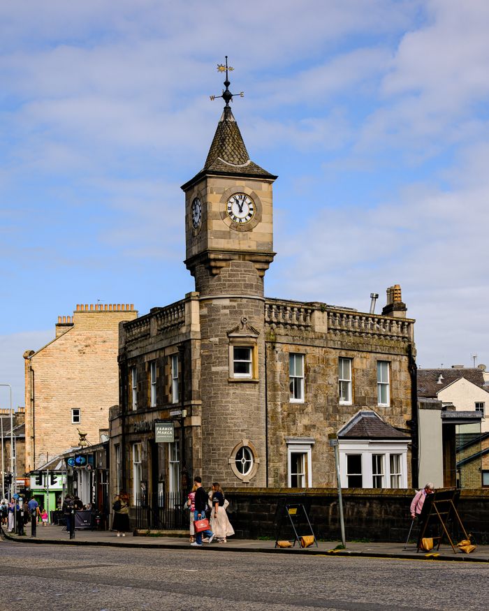 Charming historic clock tower stands proudly on a bustling street in Edinburgh, Scotland.