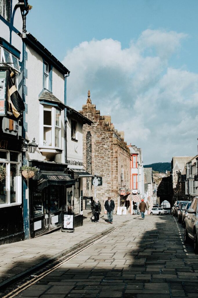 Historic street scene in Conwy, Wales with old buildings and people walking.